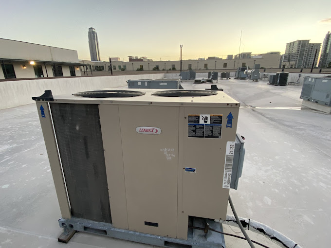 Lennox commercial rooftop AC unit maintained by Texas Heatwave with the Houston skyline at dusk